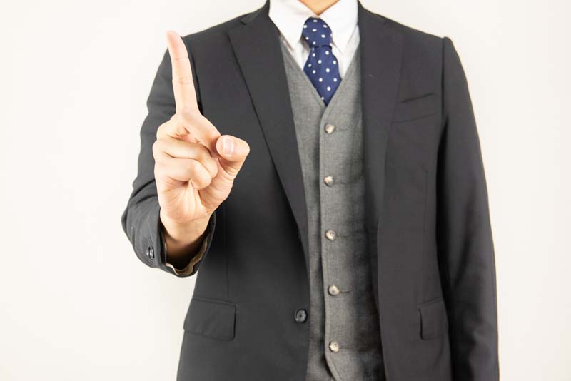 右手の人差指を立てている男性