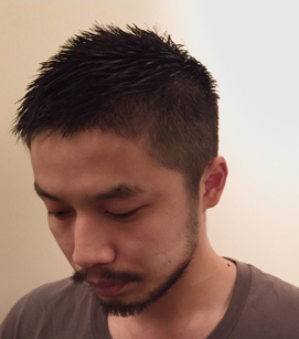 すこし俯く短髪の男性