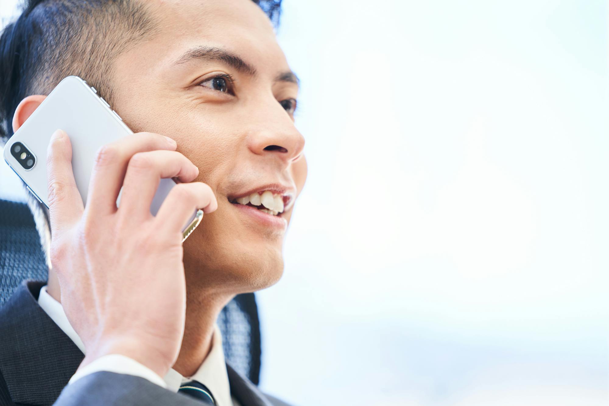 笑顔で電話する刈り上げショートヘア男性のアップ