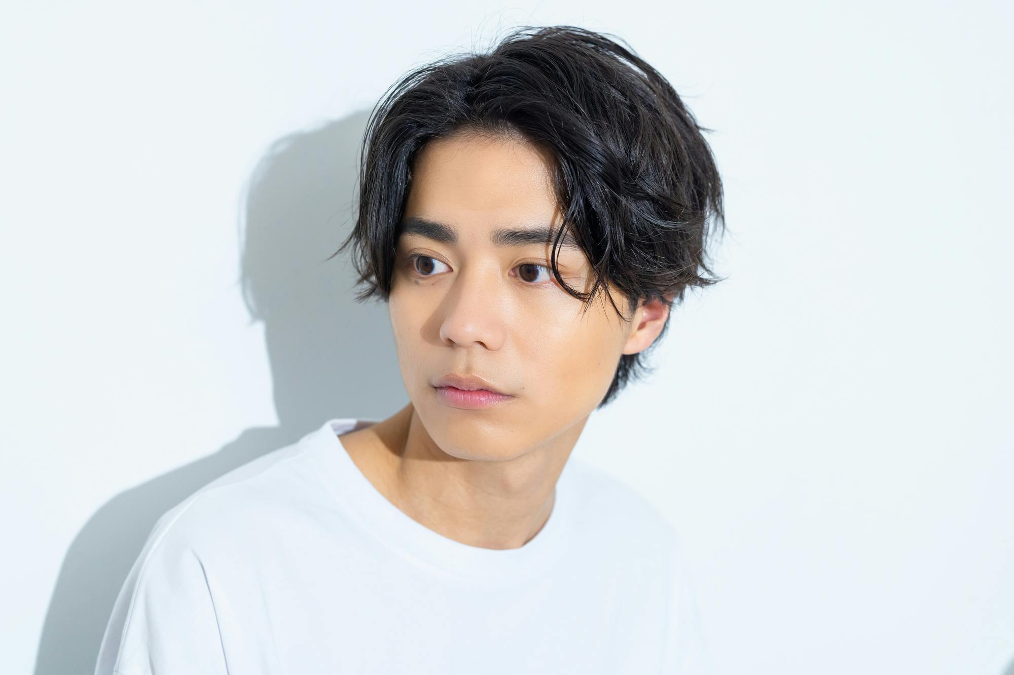 緩いウェーブ感のある髪をセンターで分けた若い男性のアップ