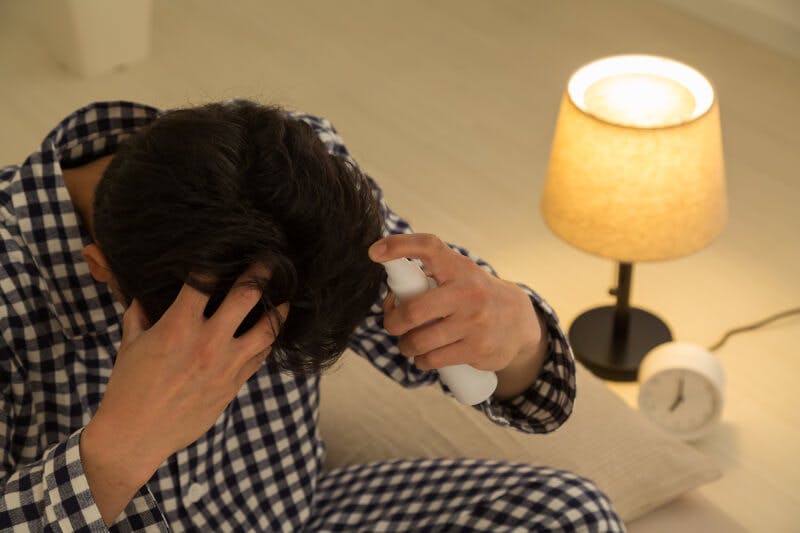 就寝前に頭皮ケアをするパジャマ姿の男性