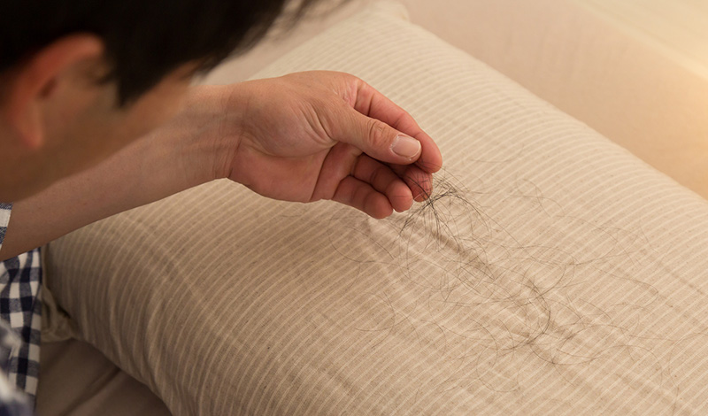 枕元に散らばる抜け毛と男性