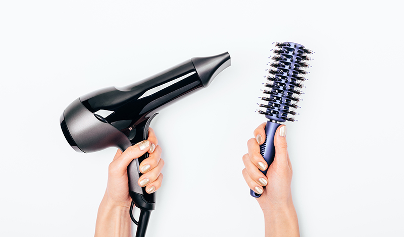 ドライヤーとクシを両手に持つ写真
