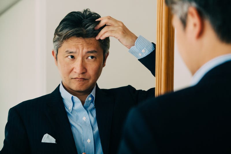 髪の様子をチェックして悩んでいる中年男性