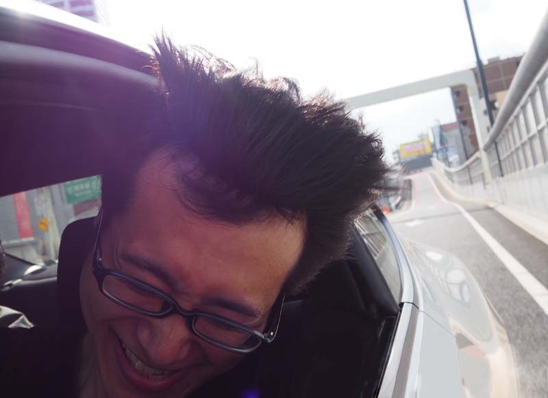 首都高のトンネルを抜け、強風に思わず下を向いてしまうコクブさん（強風で前髪が持ち上がっている様子2）