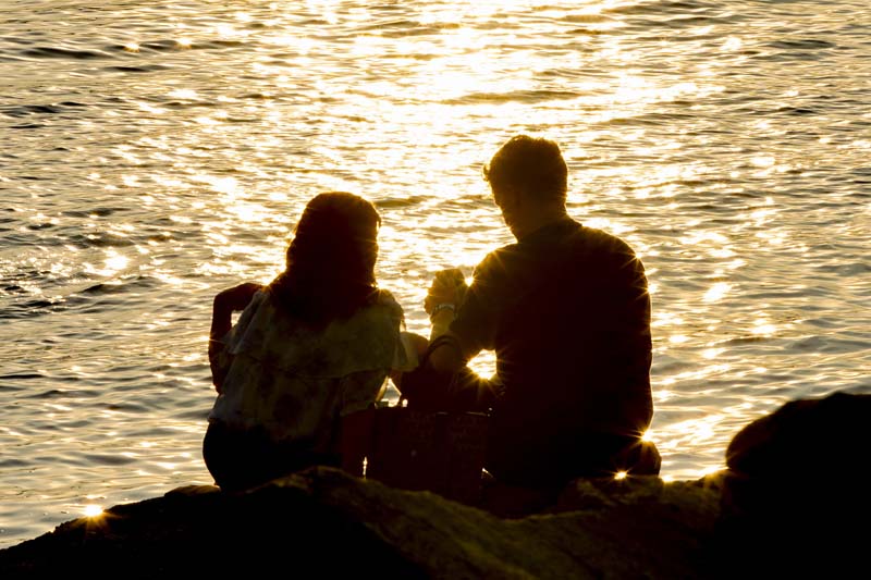 夕日を一緒に見つめる男女のシルエット