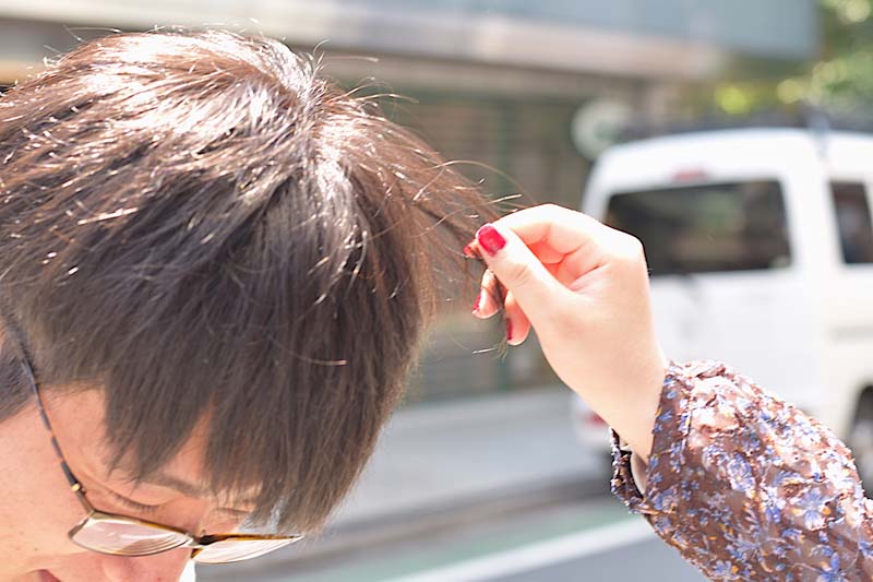 コクブさんの髪の毛に触れる女性の手