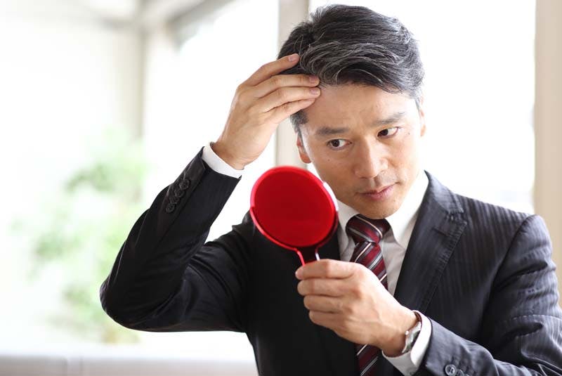 スーツを来た男性がヘアスタイルを気にしている様子