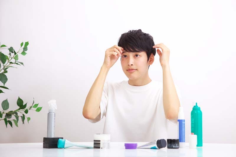 髪型をセットし直している男性のイメージ画像