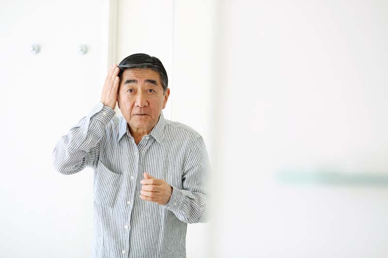 髪に手を当てて髪型を整えている男性のイメージ画像