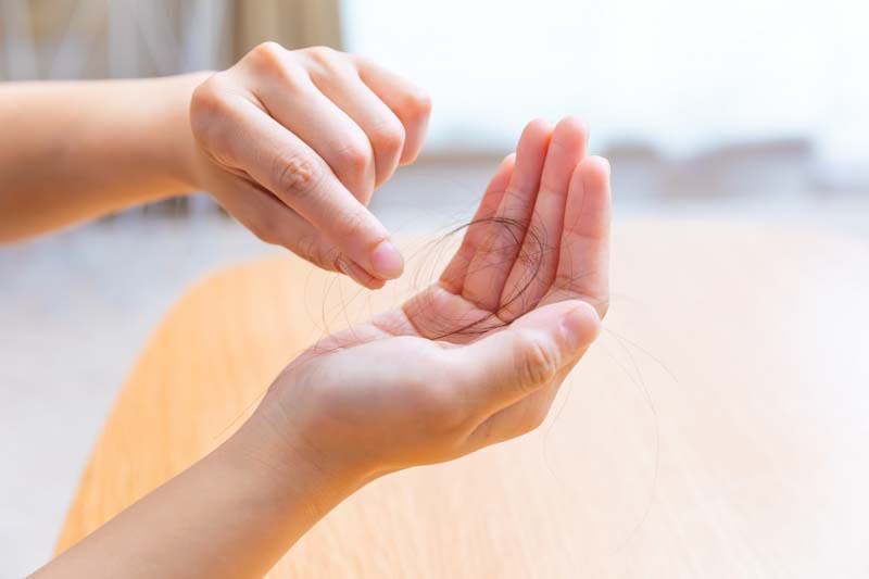 細い抜け毛を手に取る男性のイメージ画像