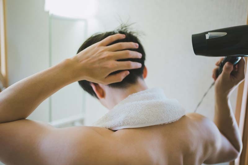 朝シャン後にドライヤーでしっかり髪を乾かしている男性のイメージ画像