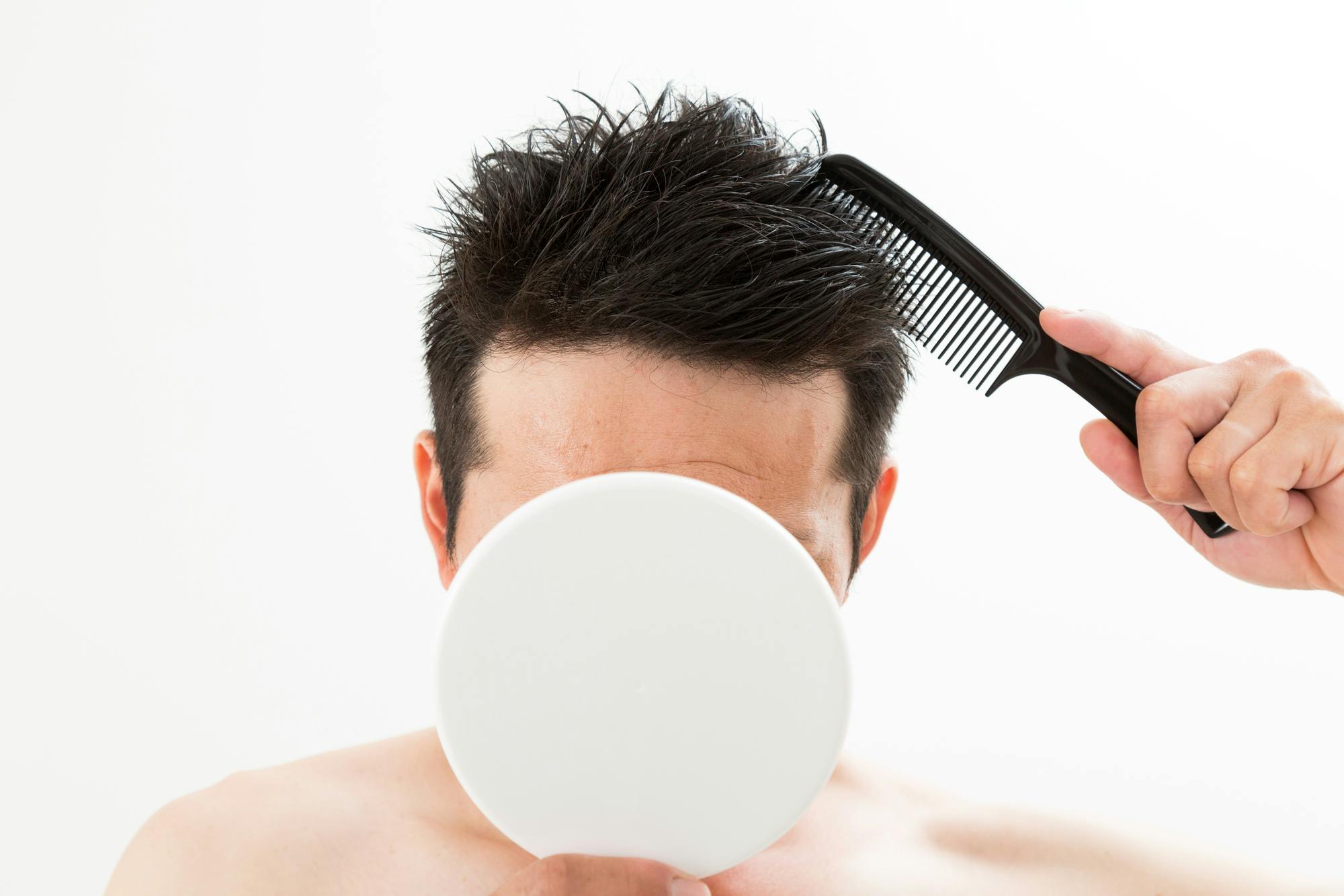 手鏡を持って髪をくしでとかす男性