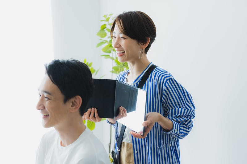 ヘアサロンで仕上がりを確認して笑顔を浮かべる男性