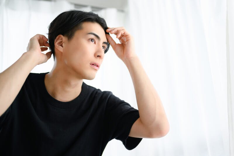 指先で増毛製品の状態をチェックする男性