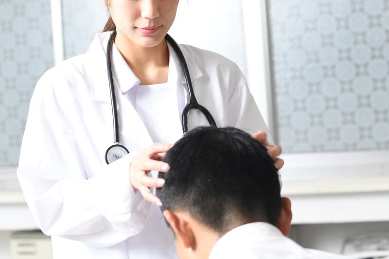 頭皮を触って診断している医師と患者