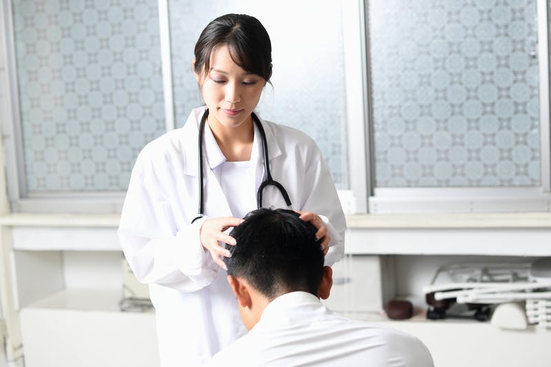 頭皮・髪の診察を受けている1人の男性