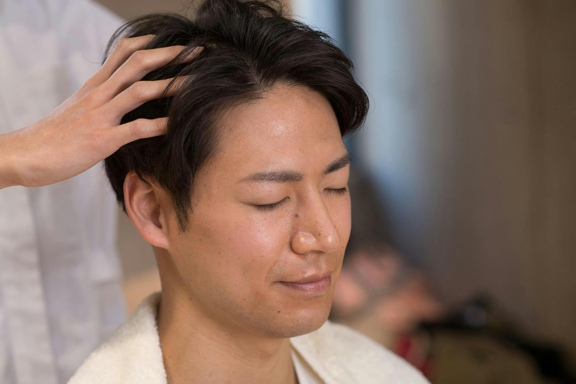 サロンで頭皮マッサージの技術を堪能するミドル男性