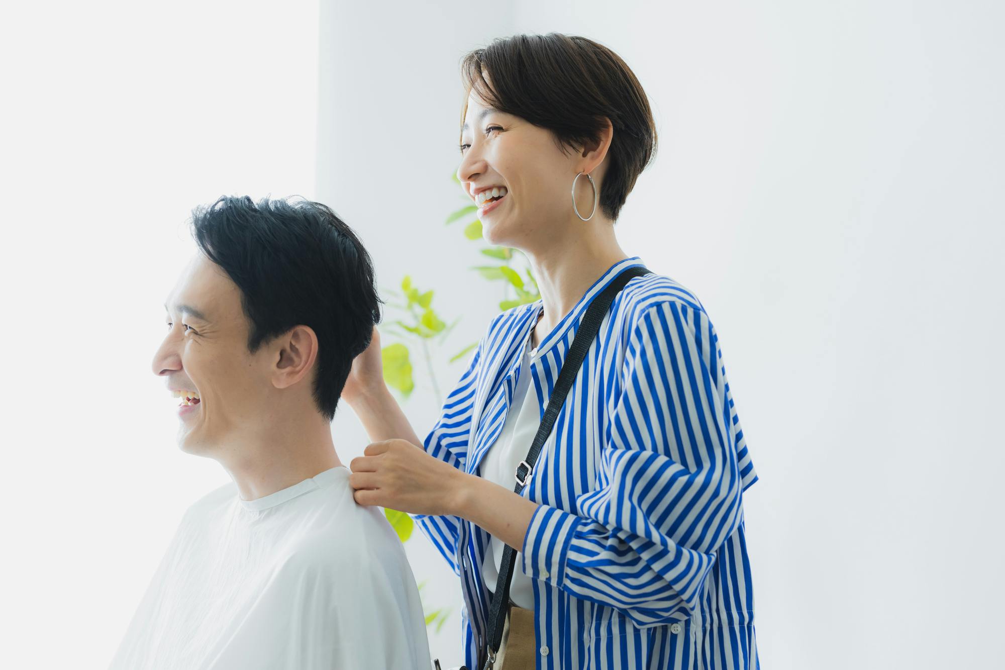 談笑するカット中の美容師と清潔なヘアスタイルの男性