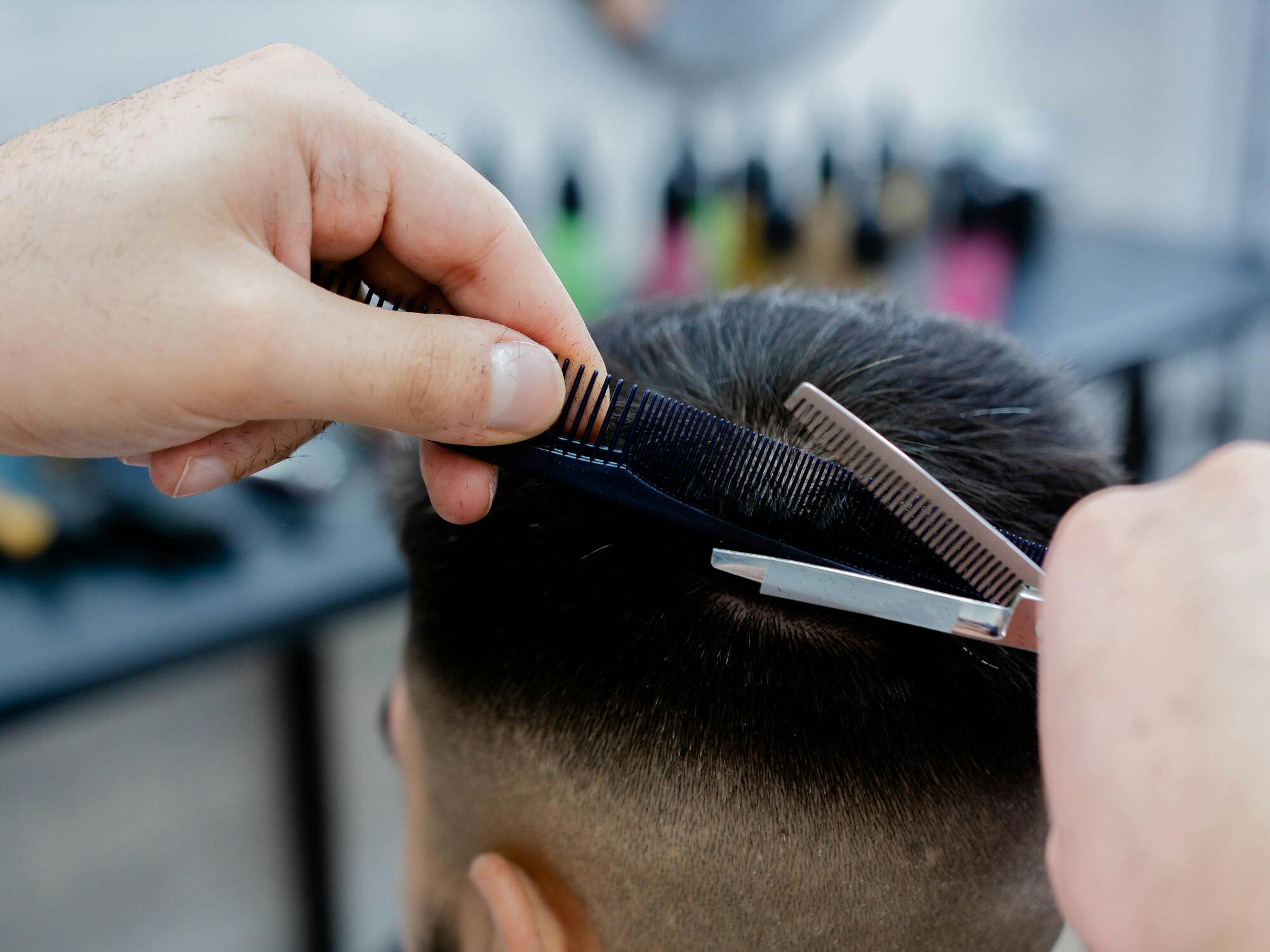 髪をカットする手と刈り上げショートヘア男性の頭部のアップ