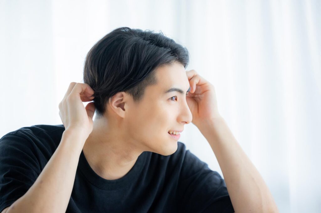 指先でかつらの収まりを確認しながら満足そうに微笑む男性