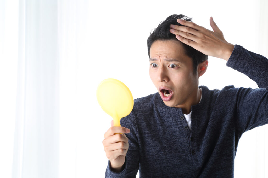 鏡を見ながら髪を確認する男性