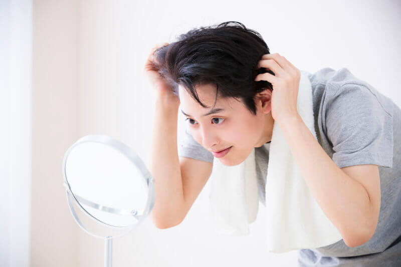 鏡を見ながら髪を整える男性