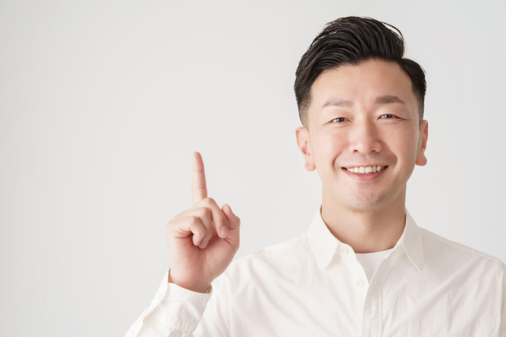 人さし指を立てて笑顔を見せる男性